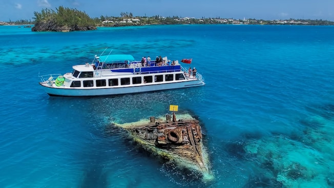 A group of people on a boat near a shipwreck A group of people on a boat near a shipwreck