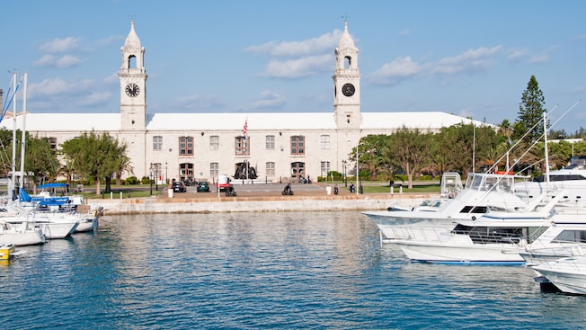 A marina full of boats near a building with 2 clock towers A marina full of boats near a building with 2 clock towers
