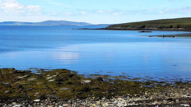 A rocky coastline along a large body of water with hills in the distance A rocky coastline along a large body of water with hills in the distance