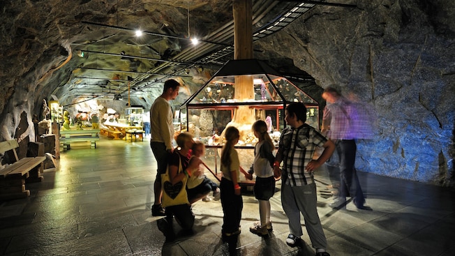 Guests of all ages view a display of gems in a museum that resembles a mine shaft
