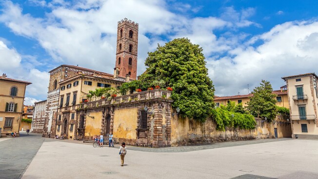 Pedestrians and bike riders taking a break to relax outside a medieval structure with a bell tower