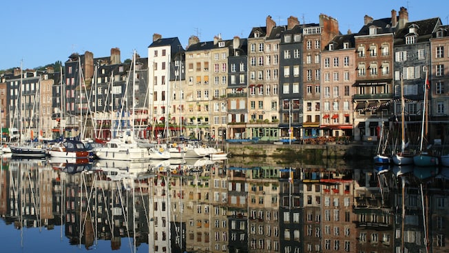 Multi-story buildings along a canal lined with sail boats Multi-story buildings along a canal lined with sail boats