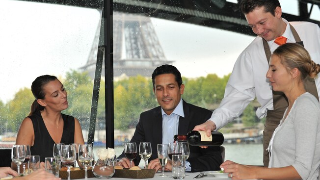 Diners sit around a table as a waiter pours wine