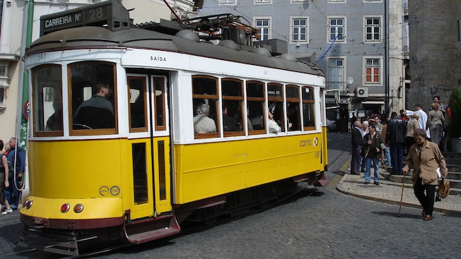 Um bonde elétrico antigo em uma esquina levando passageiros Um bonde elétrico antigo em uma esquina levando passageiros
