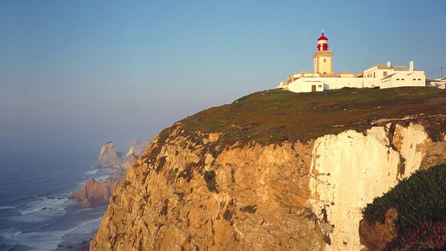 A lighthouse on a cliff that overlooks the ocean