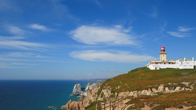 A lighthouse on a cliff that overlooks the ocean A lighthouse on a cliff that overlooks the ocean