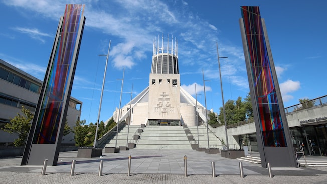 Prédio em forma de tenda com uma torre de pináculos flanqueada por 2 estruturas verticais coloridas Prédio em forma de tenda com uma torre de pináculos flanqueada por 2 estruturas verticais coloridas