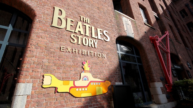 Exterior de um prédio de tijolos com as palavras The Beatles Story Exhibition acima de um gráfico submarino Exterior de um prédio de tijolos com as palavras The Beatles Story Exhibition acima de um gráfico submarino