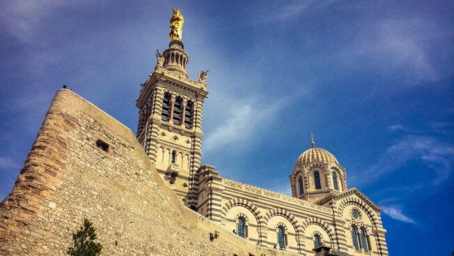 Castle walls near a cathedral topped with a golden statue