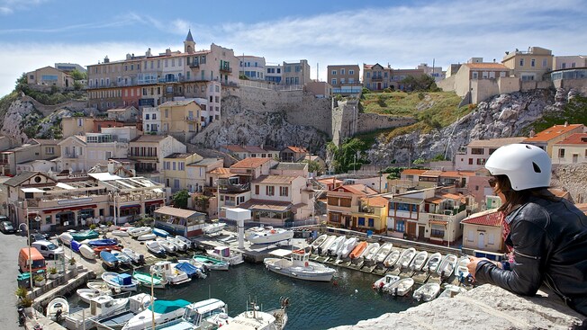 A woman looks down on a marina full of boats near buildings and houses
