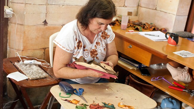 A woman at a workspace holding a mask