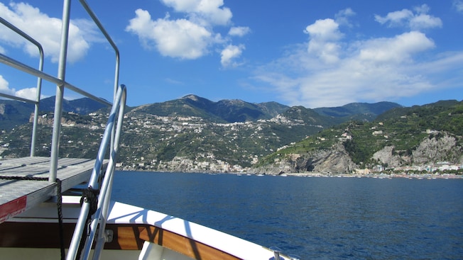 The front of a boat heading to civilization on a mountainous shoreline The front of a boat heading to civilization on a mountainous shoreline