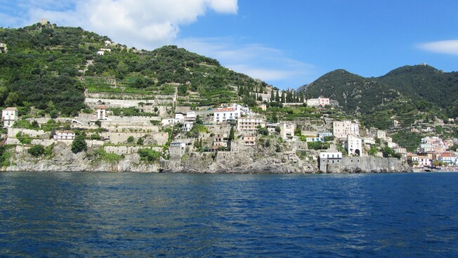 Coastal waters bordering hills featuring buildings and lush greenery