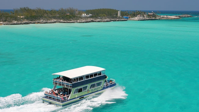A double decker ferry carries passengers toward a narrow island A double decker ferry carries passengers toward a narrow island