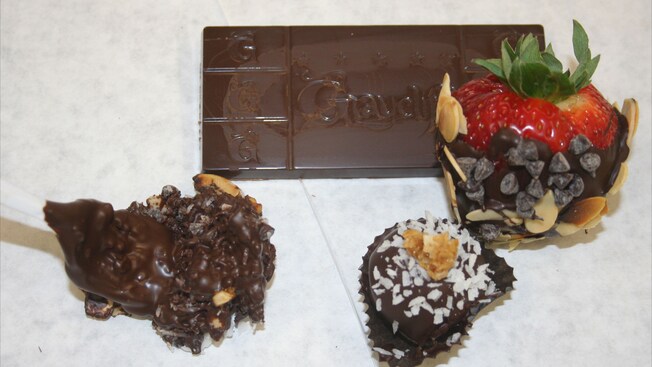 A Graycliff chocolate bar sits next to 3 pieces of chocolate coated confections