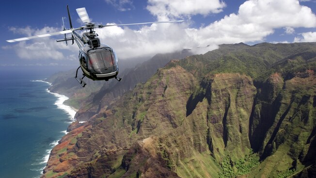 Vista aérea de un helicóptero sobre una costa y un cañón con áreas de césped y follaje