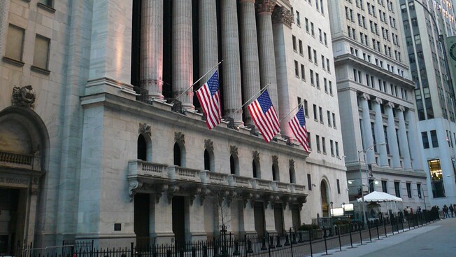Three American flags hang in front of a concrete block building with pillars along the front