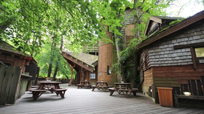 An eating area with picnic tables on a wooden deck between buildings