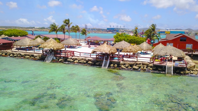 A row of cabanas near trees, bodies of water and a distant town A row of cabanas near trees, bodies of water and a distant town