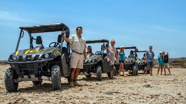 People next to UTV vehicles on rocky terrain