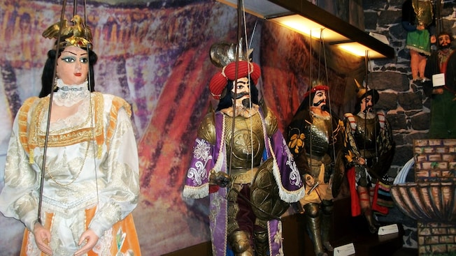 Marionetes representando uma rainha, um rei e dois soldados em frente a um fundo de teatro Marionetes representando uma rainha, um rei e dois soldados em frente a um fundo de teatro