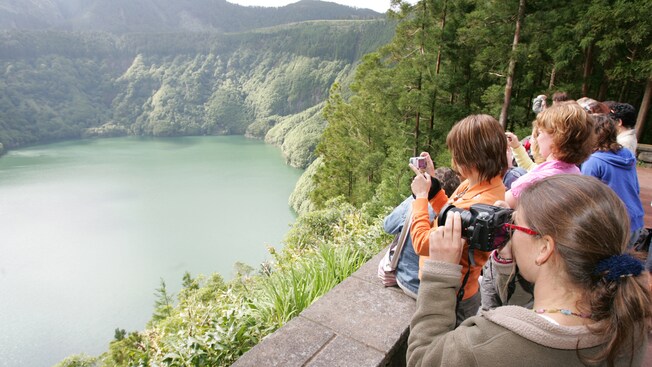 Los turistas en el punto panorámico toman fotografías de un pintoresco lago