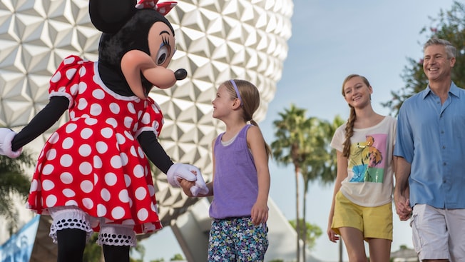 Minnie holds hands and shares a laugh with a little girl in front of Spaceship Earth Minnie holds hands and shares a laugh with a little girl in front of Spaceship Earth