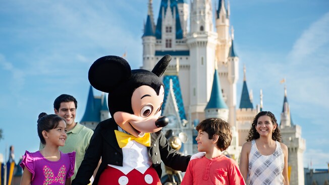 Mickey greets a little boy in front of his family and Cinderella Castle