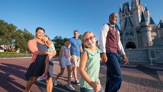 A VIP guide escorts a family of 5 Guests past Cinderella Castle