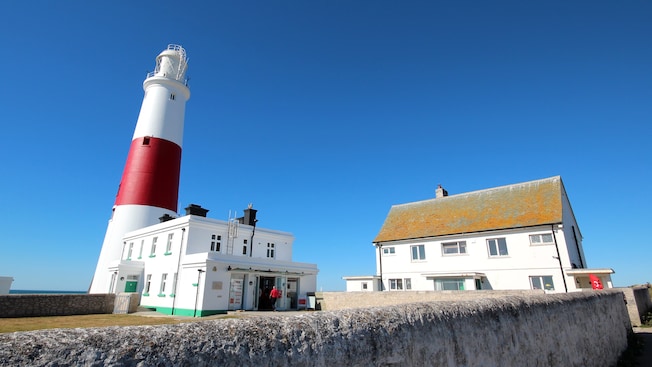 Um homem entra no Farol de Portland Bill, situado em um penhasco costeiro próximo à casa de um guardião