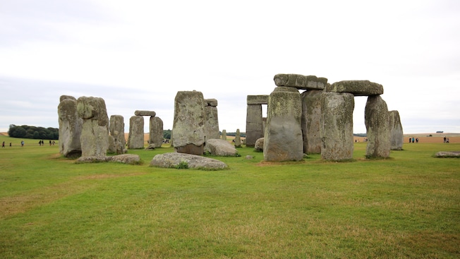 People explore the grass fields behind the monument at Stonehenge People explore the grass fields behind the monument at Stonehenge