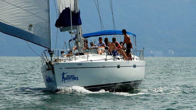 A sailboat carries several passengers in the ocean