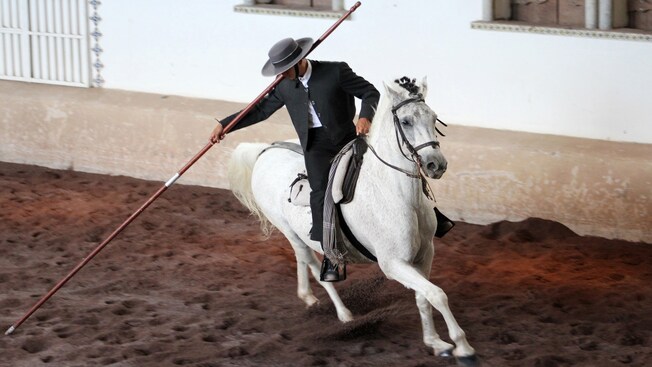A man holding a staff rides a horse