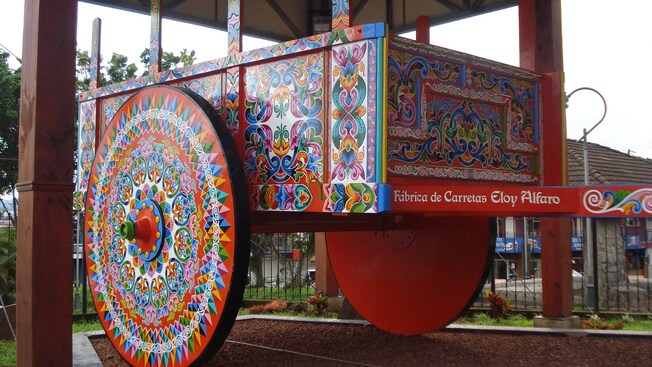 A painted oxcart with large wheels and the words Fábrica de Carretas Eloy Alfaro