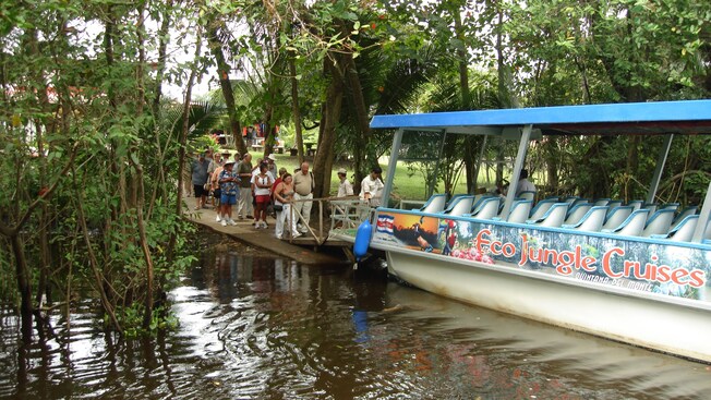 Un grupo de personas se preparan para abordar una embarcación con un letrero que dice Eco Jungle Cruises