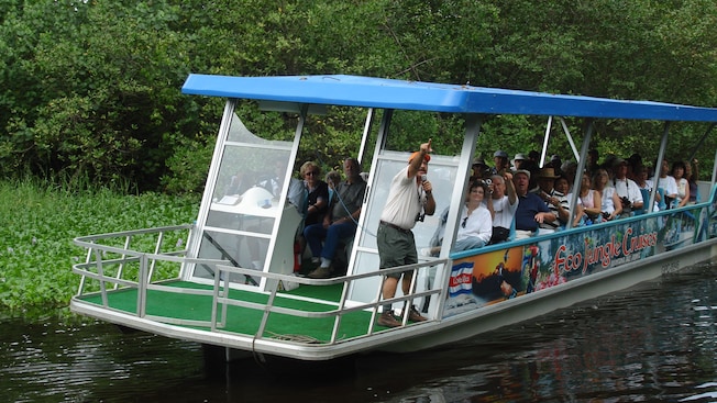A boat full of people and a tour guide with a sign that reads Eco Jungle Cruises A boat full of people and a tour guide with a sign that reads Eco Jungle Cruises