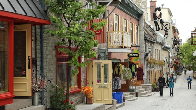 Pedestrians stroll along a quaint street lined with cafes and boutiques Pedestrians stroll along a quaint street lined with cafes and boutiques