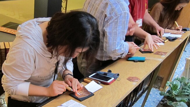 Guests use tools to create embossed copper design