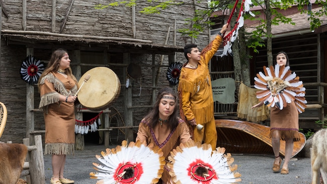 Three women and a man in traditional native outfits perform a dance Three women and a man in traditional native outfits perform a dance