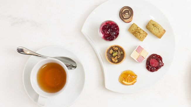 Tea accompanied by cookies, tartes, biscuits, raspberry jam and orange marmalade
