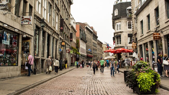 People walk down a storefront lined street in a city