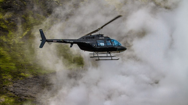 A helicopter flying over the thick smoke of a volcano A helicopter flying over the thick smoke of a volcano