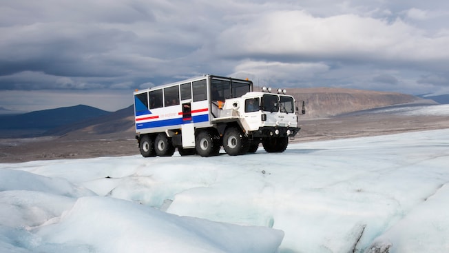 Mountains stand in the background of a heavy duty transport vehicle parked on the ice
