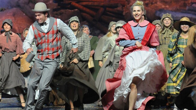 A man and woman dressed in costumes from the early 20th century lead the dancing