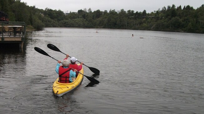 Dois Visitantes em um passeio de canoa para 2 lugares em um lago arborizado