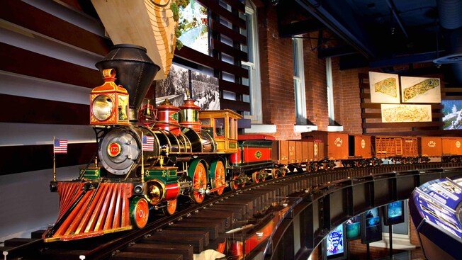 A model on tracks in a modern museum with brownstone walls