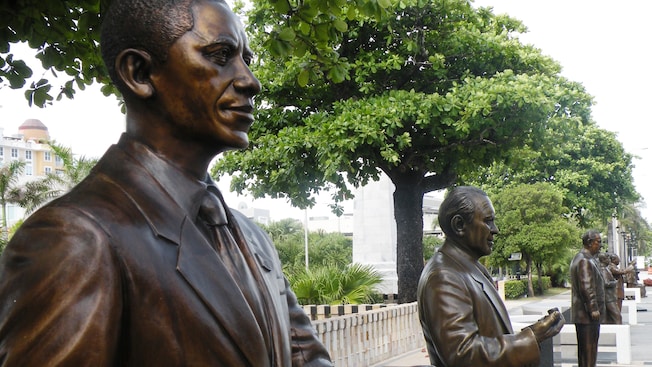 A row of statues near trees and a park A row of statues near trees and a park