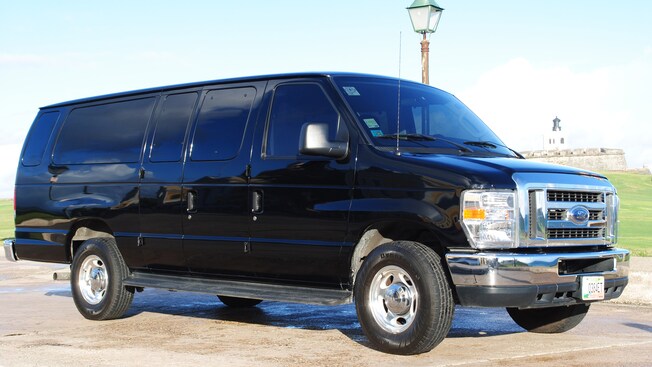 A large van with tinted windows sits in front of a lamp post with a stone fort in the far distance