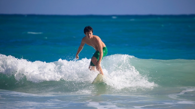 Un adolescente sobre una tabla de surf en una ola Un adolescente sobre una tabla de surf en una ola