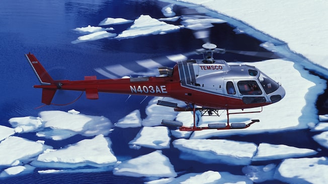 A helicopter flying over a series of snow floes A helicopter flying over a series of snow floes